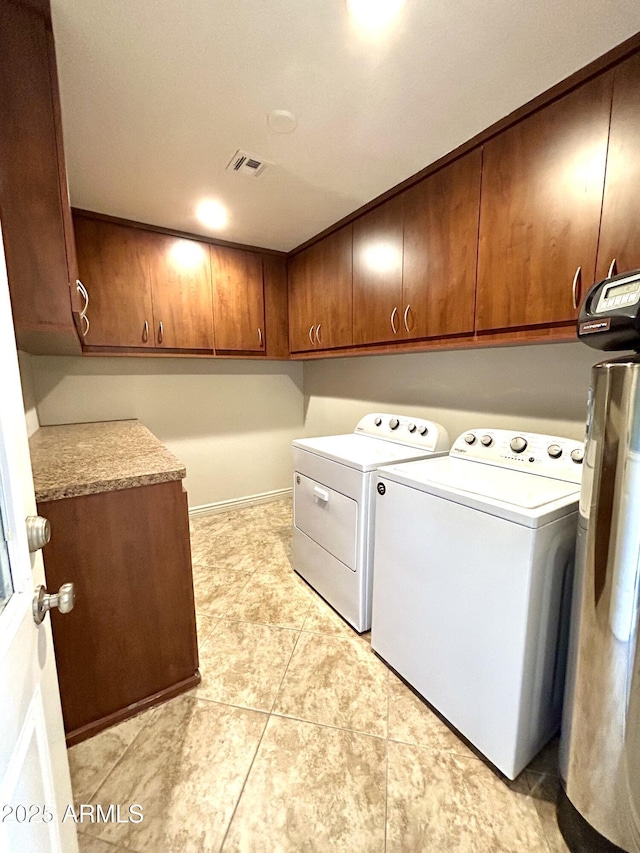 washroom featuring washer and dryer, cabinet space, visible vents, and light tile patterned floors