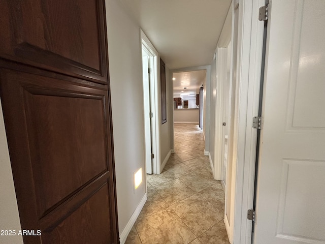 hallway with baseboards and light tile patterned floors