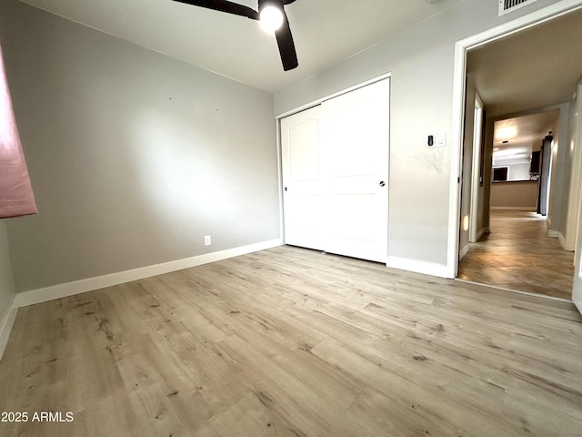 unfurnished bedroom with baseboards, a ceiling fan, wood finished floors, and a closet