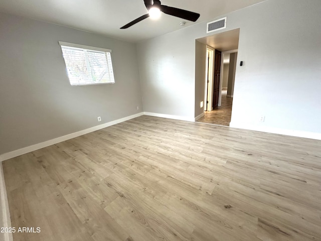 spare room featuring wood finished floors, baseboards, a ceiling fan, and visible vents