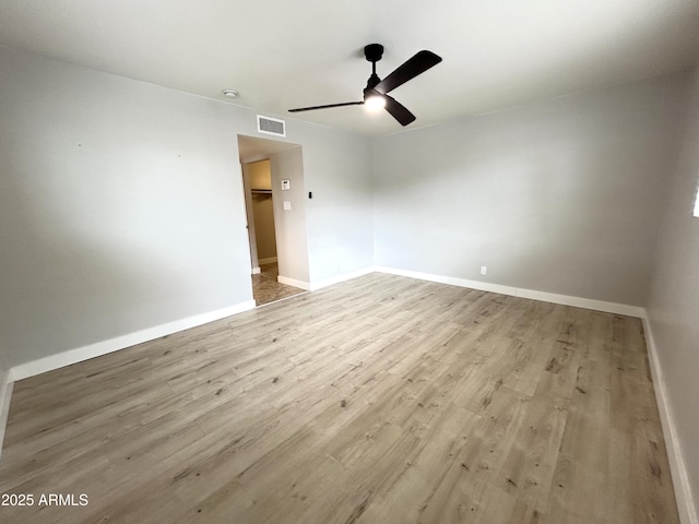 unfurnished room with baseboards, a ceiling fan, wood finished floors, and visible vents