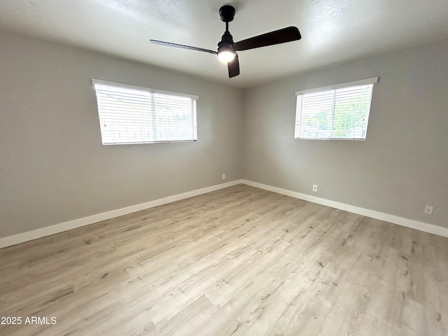 empty room featuring baseboards, wood finished floors, ceiling fan, and a healthy amount of sunlight