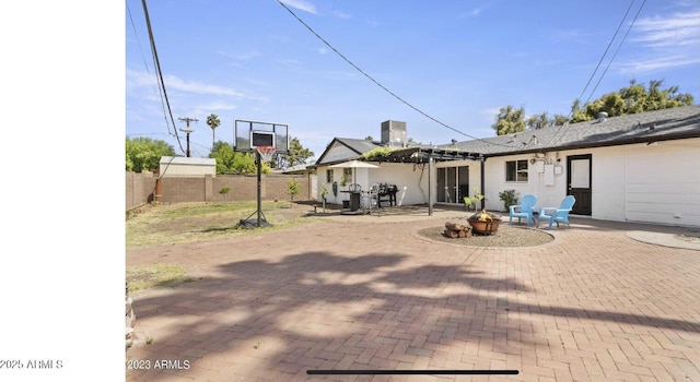 rear view of house with a pergola, a fenced backyard, stucco siding, a patio, and an outdoor fire pit