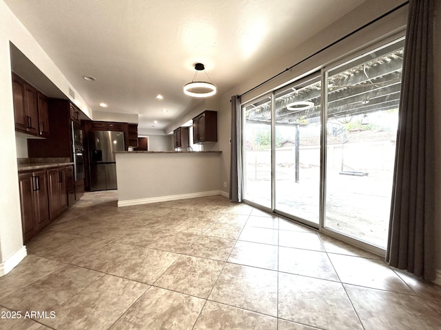 kitchen featuring light tile patterned flooring, baseboards, dark brown cabinetry, a peninsula, and stainless steel refrigerator with ice dispenser