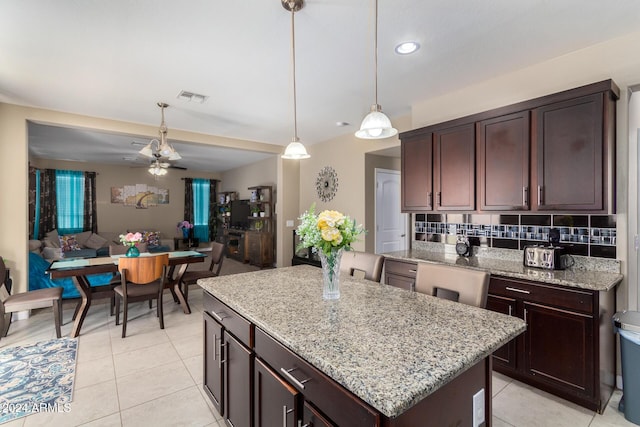 kitchen featuring decorative backsplash, visible vents, ceiling fan, decorative light fixtures, and a center island
