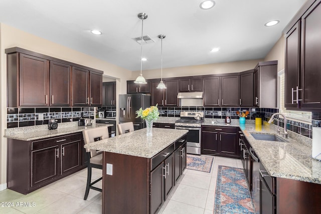 kitchen with a kitchen island, appliances with stainless steel finishes, dark brown cabinetry, under cabinet range hood, and a sink
