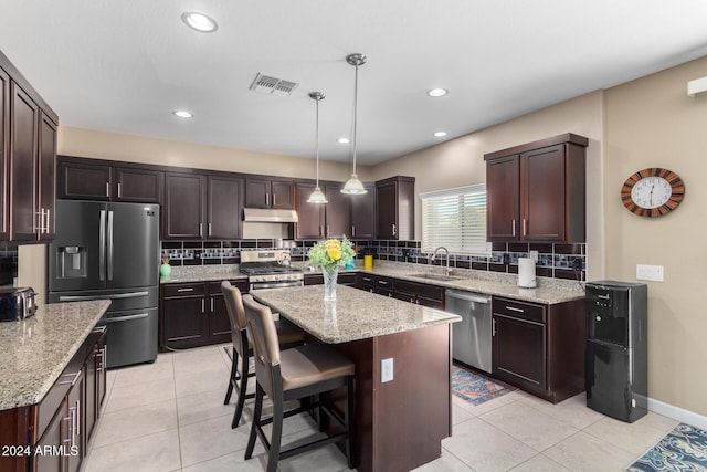 kitchen with stainless steel appliances, under cabinet range hood, a sink, light tile patterned flooring, and visible vents