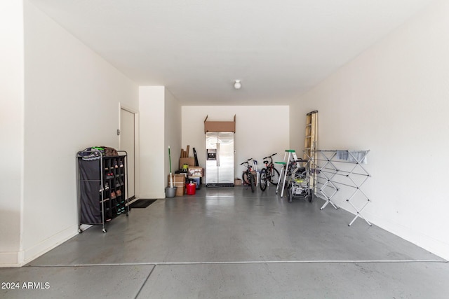 garage with baseboards and stainless steel refrigerator with ice dispenser