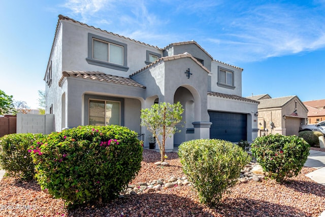 mediterranean / spanish house featuring stucco siding, a garage, and a tiled roof