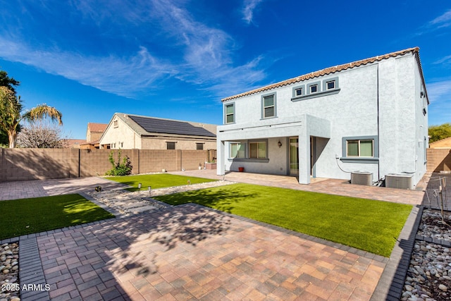 back of property featuring a fenced backyard, central AC, stucco siding, and a patio