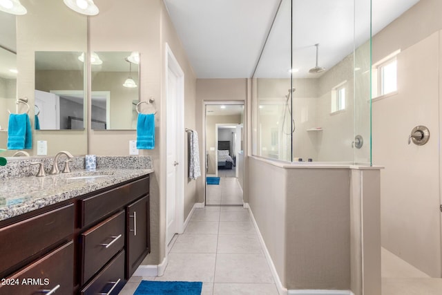 ensuite bathroom featuring vanity, baseboards, tile patterned floors, ensuite bath, and a walk in shower
