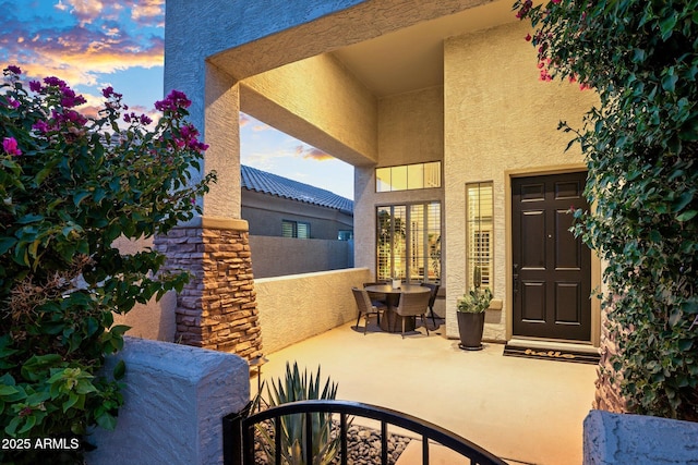 2056 E Carob Dr, Chandler, AZ 85286 - exterior entry at dusk with stucco siding, outdoor dining area, and a balcony