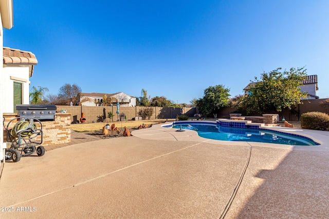 view of pool with area for grilling, a patio, and an outdoor kitchen