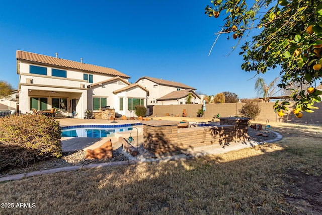 rear view of house with a fenced in pool and a patio area