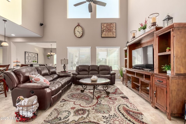 living room with a towering ceiling and ceiling fan with notable chandelier