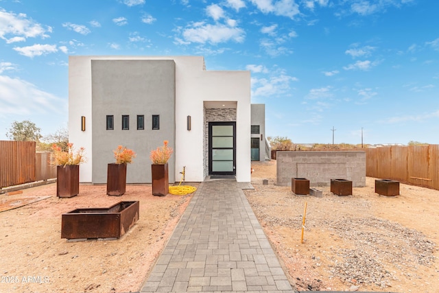 view of front of home featuring stucco siding and fence private yard