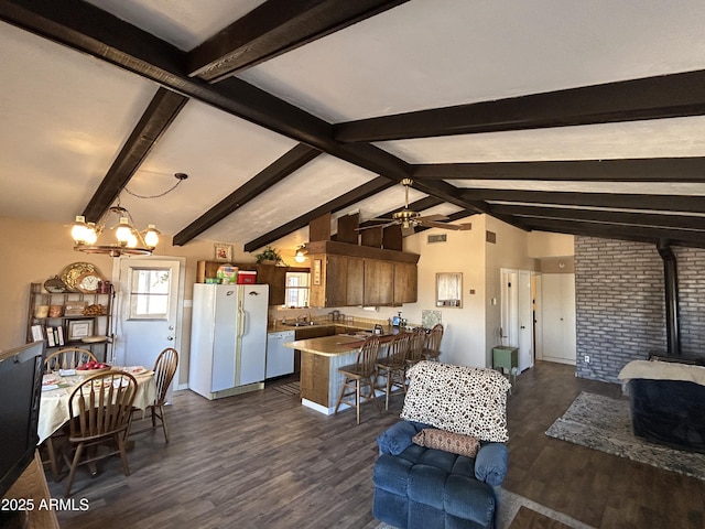 living area featuring ceiling fan with notable chandelier, dark wood-type flooring, a wood stove, and vaulted ceiling with beams