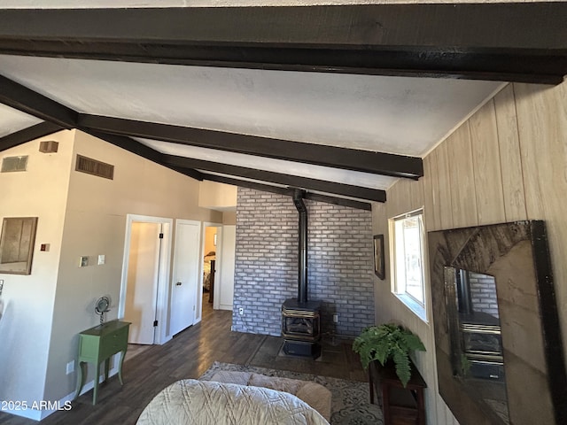 living room with vaulted ceiling with beams, dark wood-style flooring, wood walls, visible vents, and a wood stove