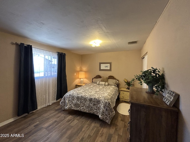 bedroom with dark wood-style floors and visible vents