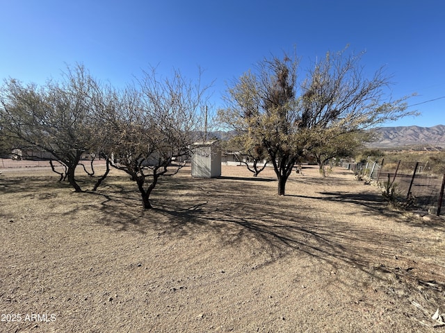 view of yard featuring fence, a mountain view, and a rural view