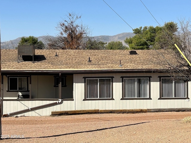 back of house with a shingled roof and a mountain view