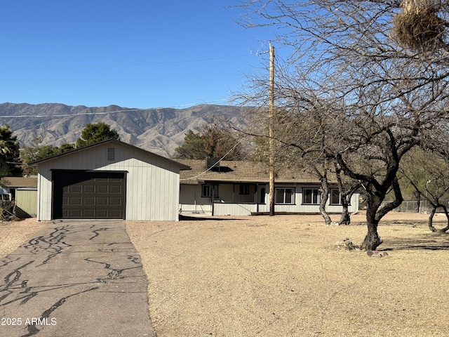 view of front of home with a mountain view, aphalt driveway, and an outdoor structure