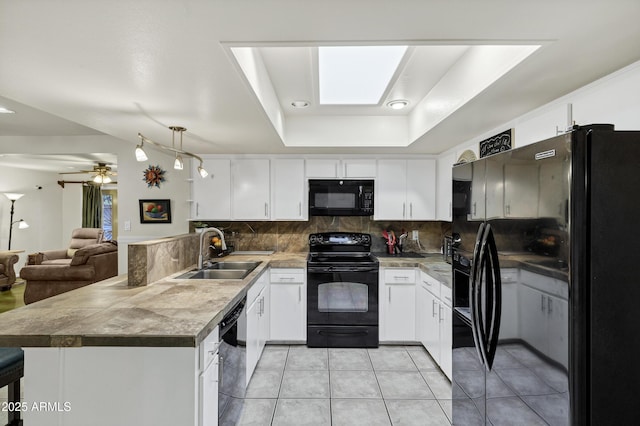 kitchen featuring sink, a tray ceiling, black appliances, and white cabinets