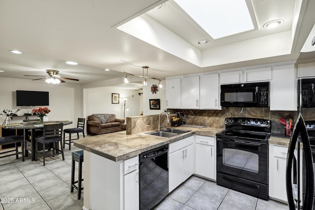 kitchen with sink, tasteful backsplash, black appliances, kitchen peninsula, and white cabinets