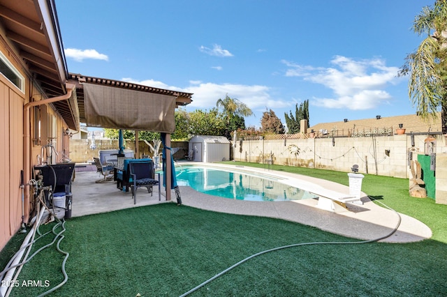 view of swimming pool with a shed, a diving board, a lawn, and a patio