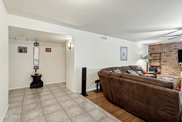 living room featuring a brick fireplace, light hardwood / wood-style floors, and ceiling fan