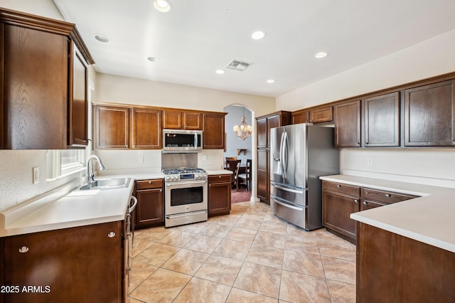 3905 S Bridal Vail Dr, Gilbert, AZ 85297 - kitchen with stainless steel appliances, a sink, light countertops, arched walkways, and recessed lighting