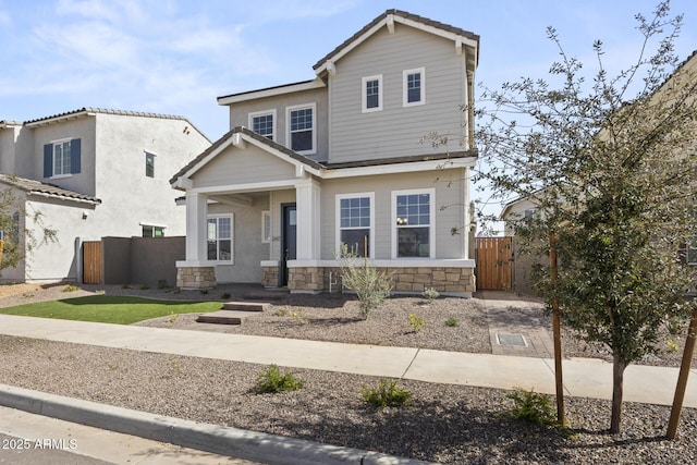 view of front of property featuring stone siding and fence