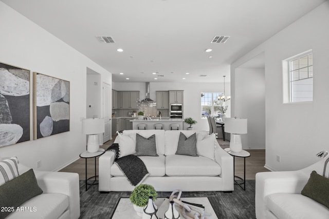 living room with recessed lighting, visible vents, dark wood-style flooring, and a chandelier