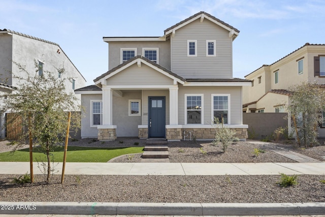 view of front of house featuring a tile roof, fence, and stone siding