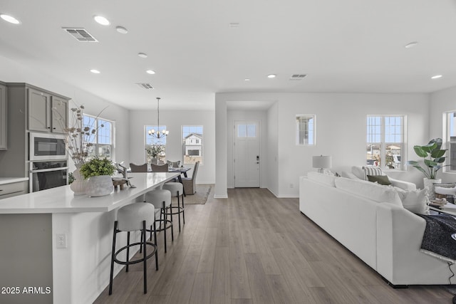 kitchen with visible vents, a breakfast bar, light wood-style flooring, gray cabinets, and appliances with stainless steel finishes