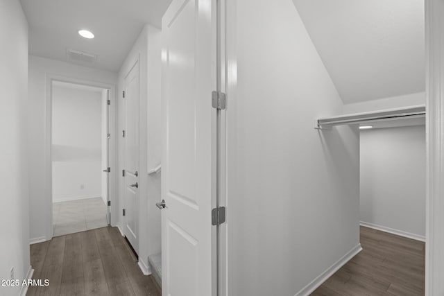 corridor featuring visible vents, baseboards, and wood finished floors