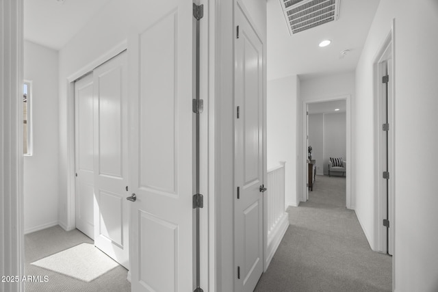 hallway with recessed lighting, light colored carpet, visible vents, and baseboards