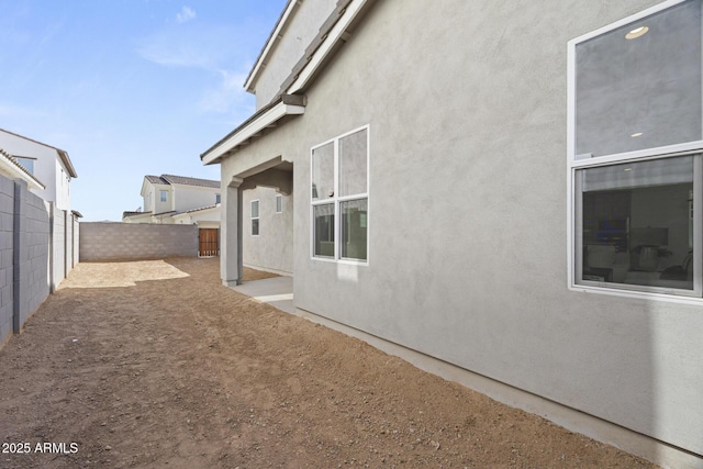 view of side of home featuring stucco siding and a fenced backyard