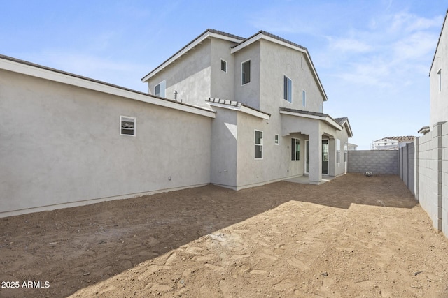 back of house with stucco siding, a fenced backyard, and a tile roof