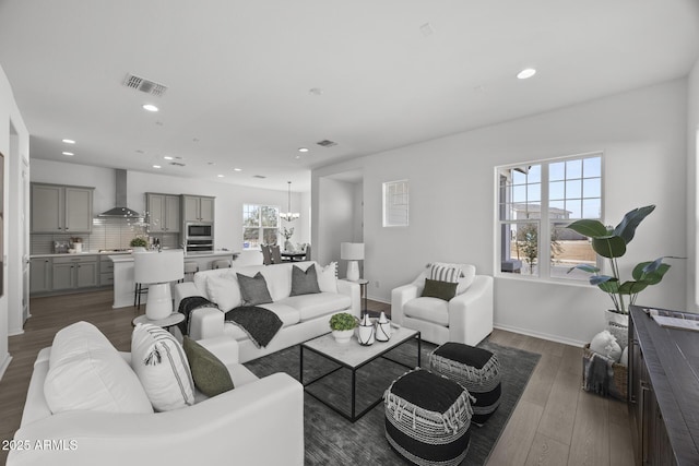 living area featuring visible vents, recessed lighting, dark wood-type flooring, and an inviting chandelier