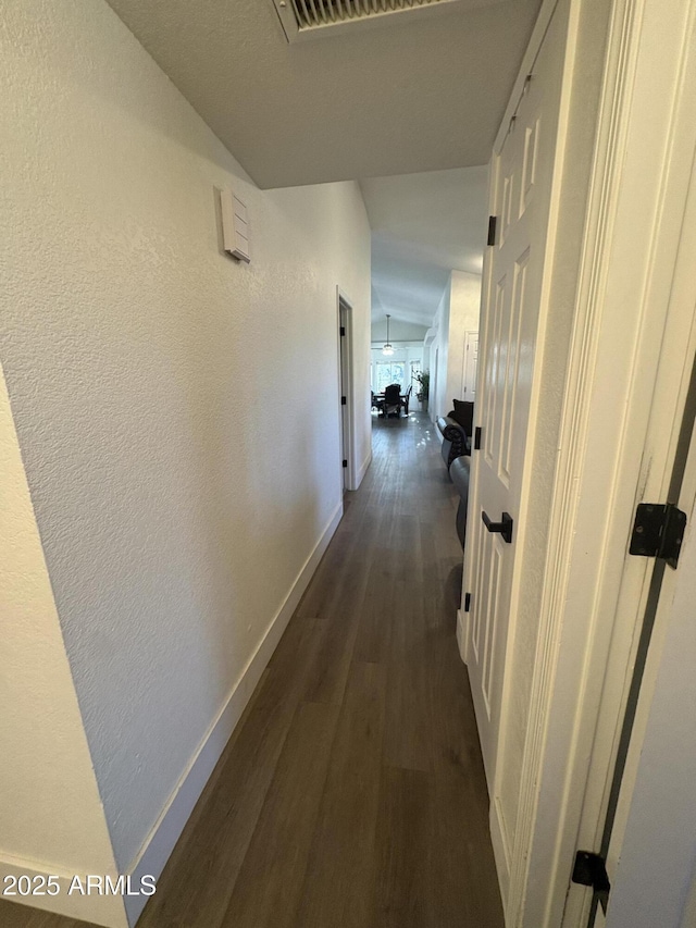 corridor with vaulted ceiling and dark hardwood / wood-style floors