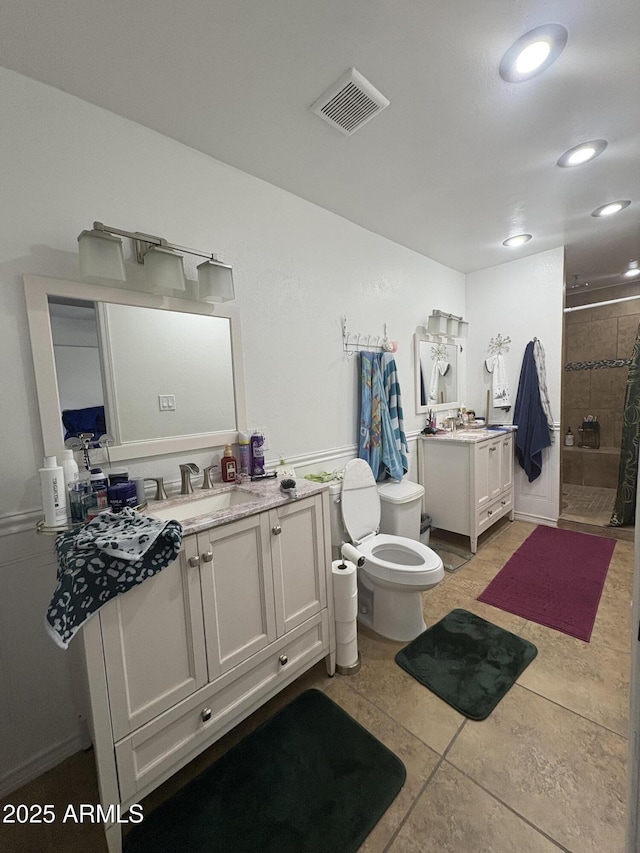 bathroom with tile patterned floors, vanity, toilet, and tiled shower