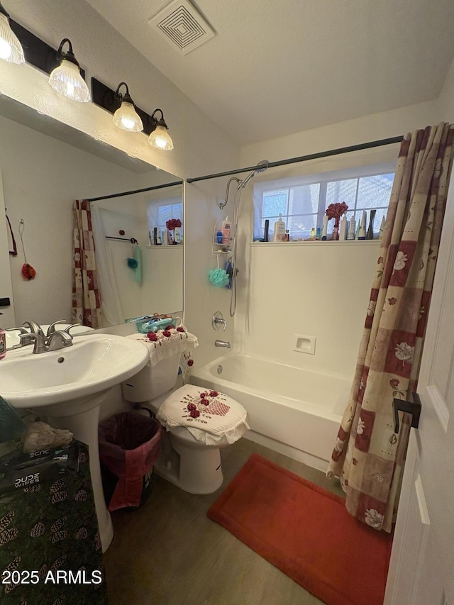 bathroom featuring hardwood / wood-style floors, shower / bath combination with curtain, and toilet