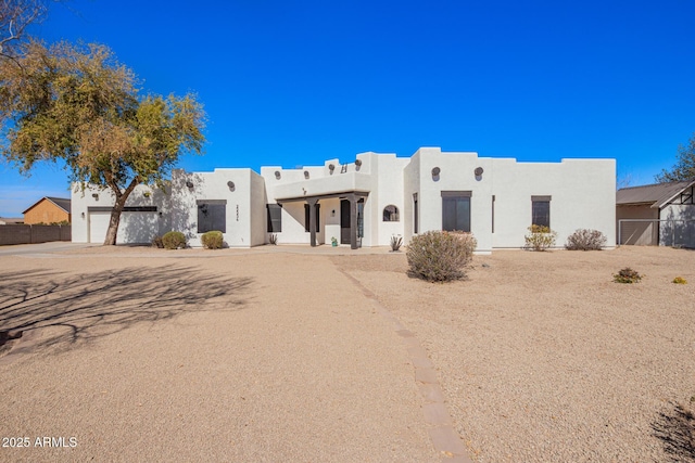 pueblo revival-style home featuring fence and stucco siding