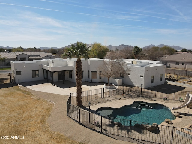 rear view of property with a fenced in pool, a patio, fence, a mountain view, and stucco siding