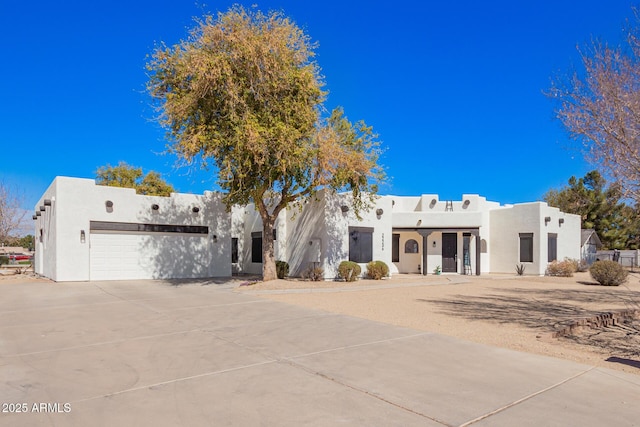 adobe home featuring concrete driveway, an attached garage, and stucco siding