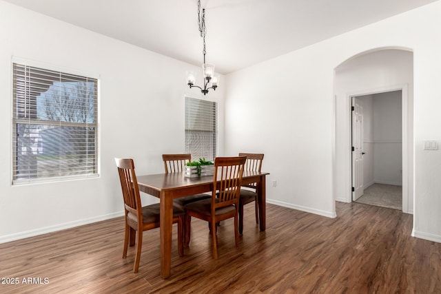 dining room featuring baseboards, arched walkways, and wood finished floors