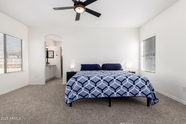 bedroom featuring carpet floors, baseboards, arched walkways, and ceiling fan