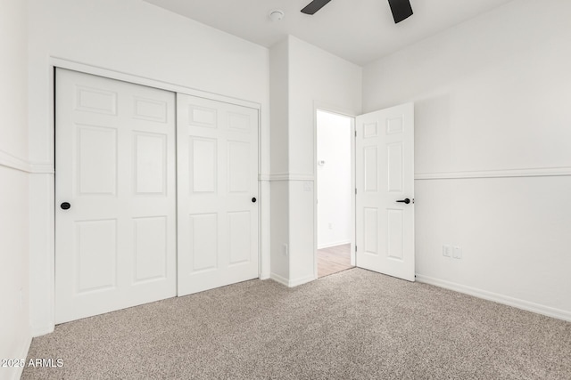 unfurnished bedroom with a closet, carpet flooring, ceiling fan, and baseboards