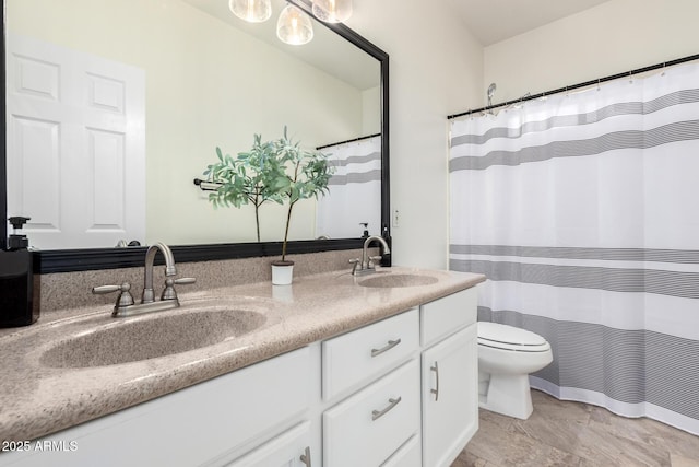 bathroom featuring double vanity, toilet, and a sink